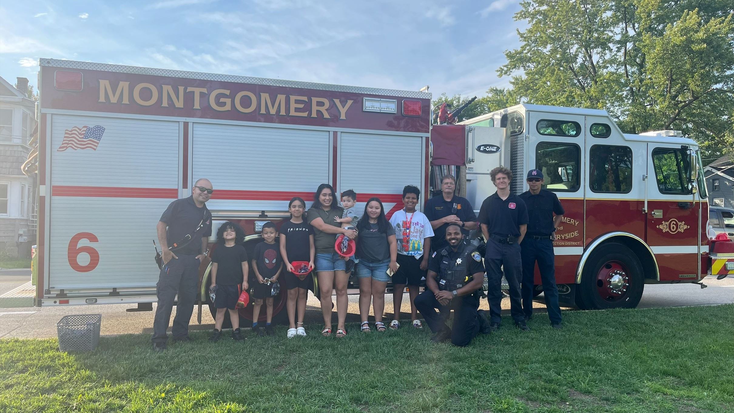 Officer and Firemen with fire engine and kids